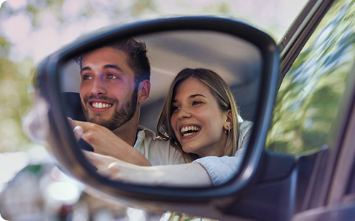 Mann sitzt in seinem neuen Auto und lächelt