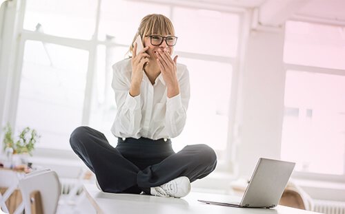 Frau sitzt am Tisch und telefoniert