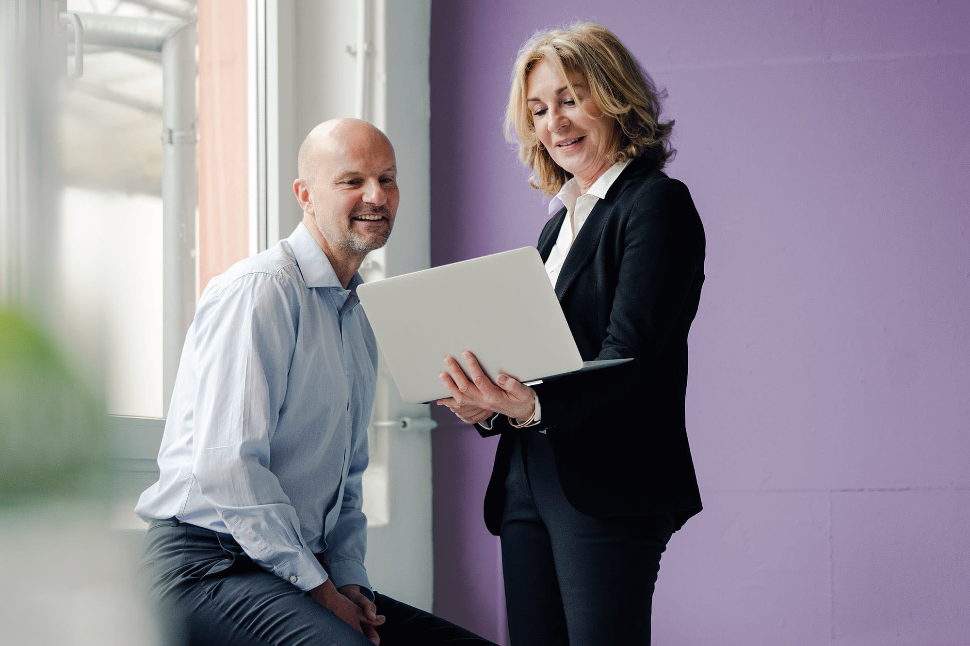 Dva zaposlena skupaj gledata na prenosni računalnik - naložbeni produkti BKS Bank Dva zaposlena skupaj gledata na prenosni računalnik - naložbeni produkti BKS Bank