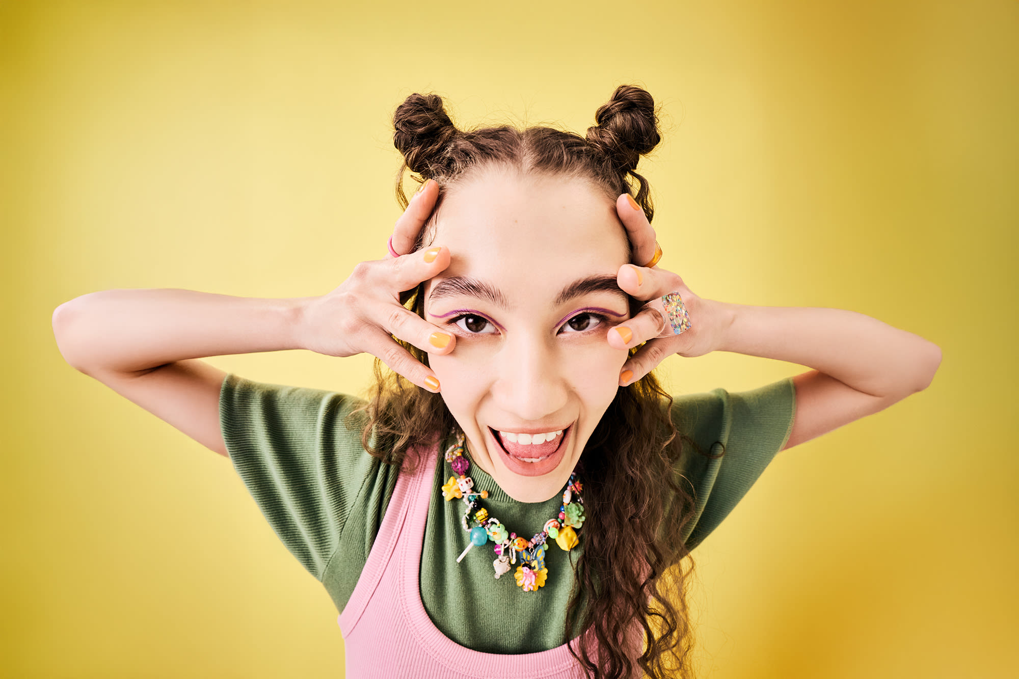 Mlada ženska z dvema čopkoma se smeji in dela smešne poze. Začetni paket pri BKS Bank.