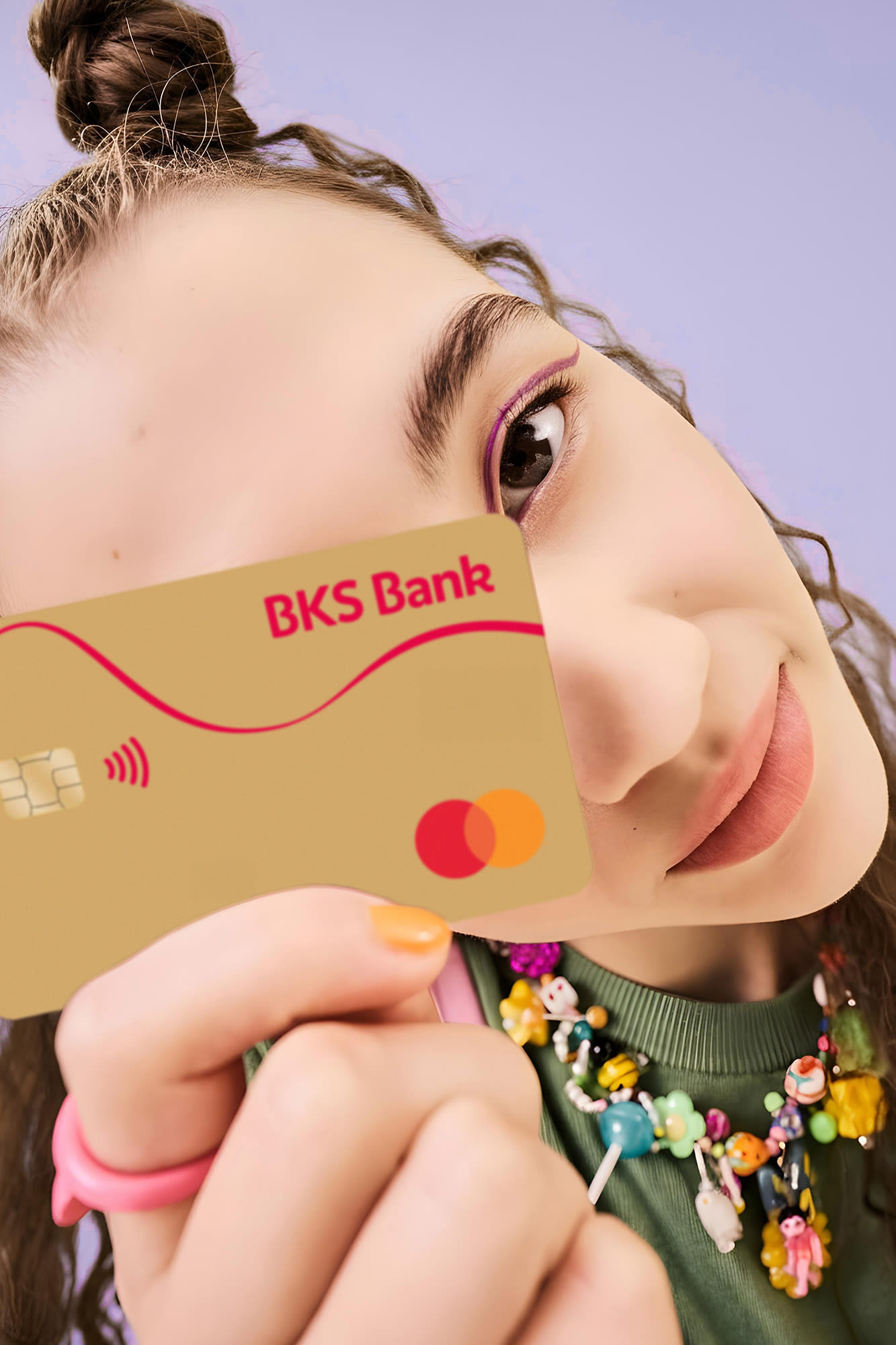 Frau mit BKS-Bank-Karte vor violettem Hintergrund – BKS Mastercard Gold Frau mit BKS-Bank-Karte vor violettem Hintergrund – BKS Mastercard Gold