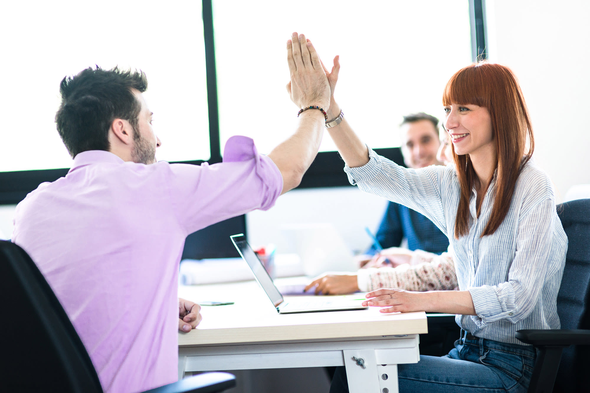 Dva sodelavca si v pisarni dasta petko - uspešno timsko delo v družbi BKS.