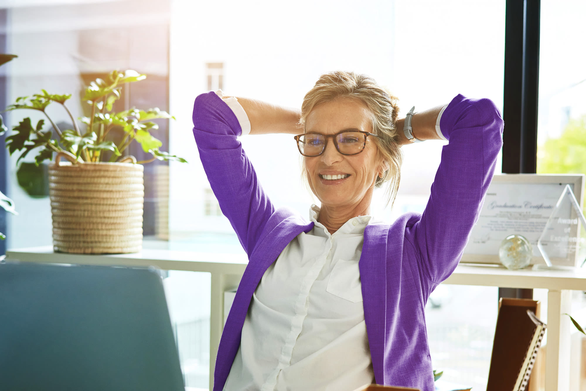 Ženska v pisarni se nasloni na hrbet in se sprosti - z družbo BKS doživi finančno varnost.