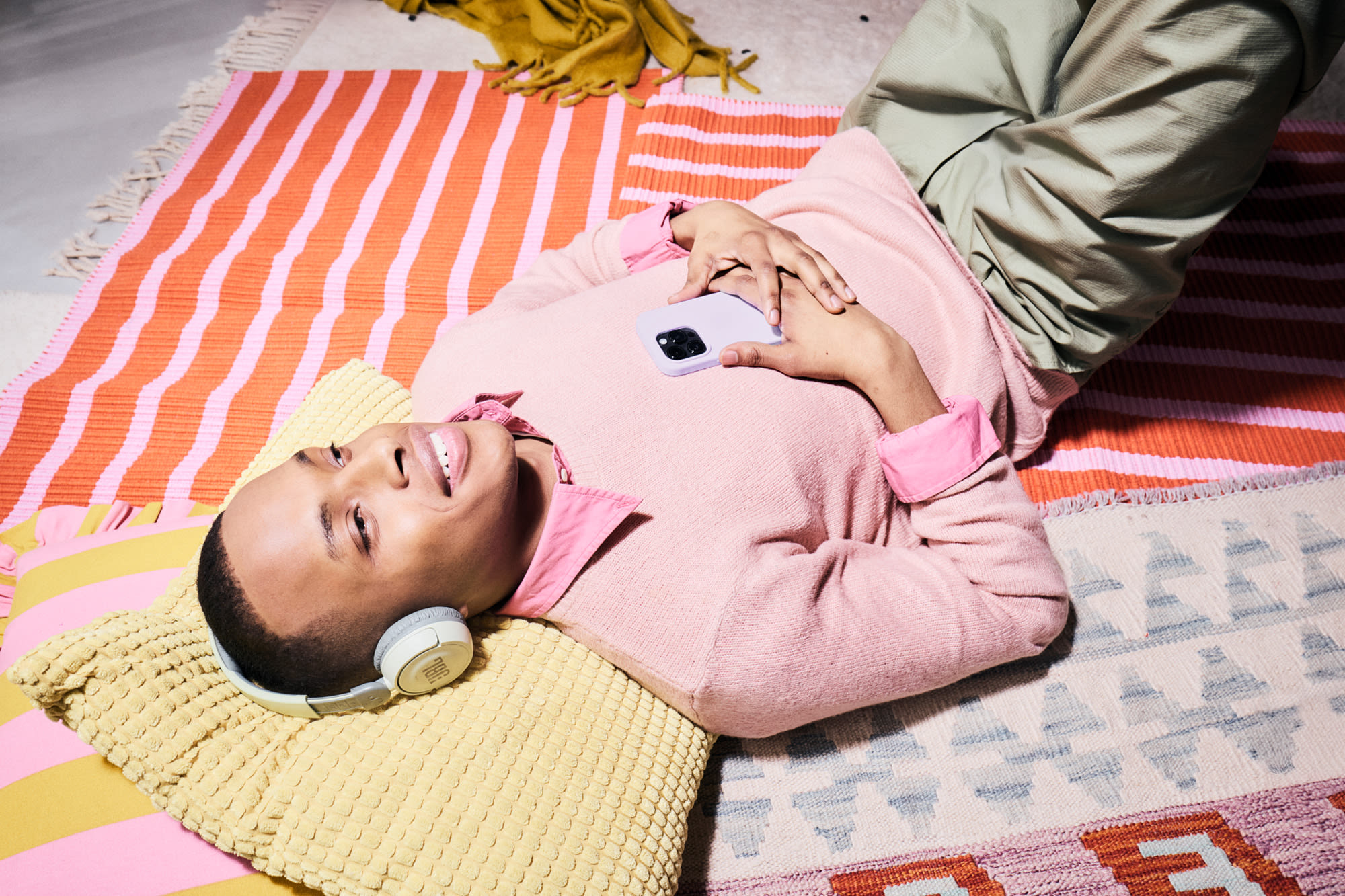 Mlada oseba s pametnim telefonom, ki leži na tleh - priročno vlaganje z BKS Bank's Komfort-Depot.