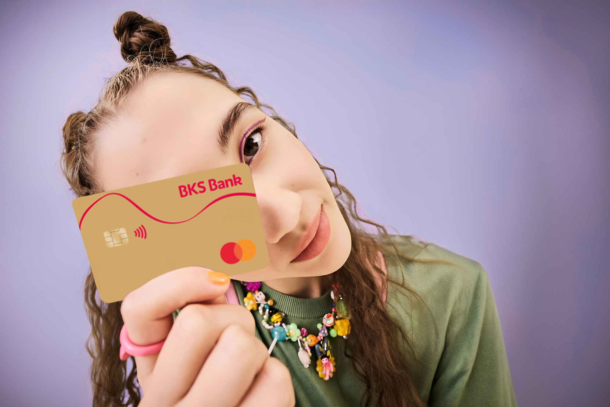 Frau mit BKS-Bank-Karte vor violettem Hintergrund – BKS Mastercard Gold Frau mit BKS-Bank-Karte vor violettem Hintergrund – BKS Mastercard Gold