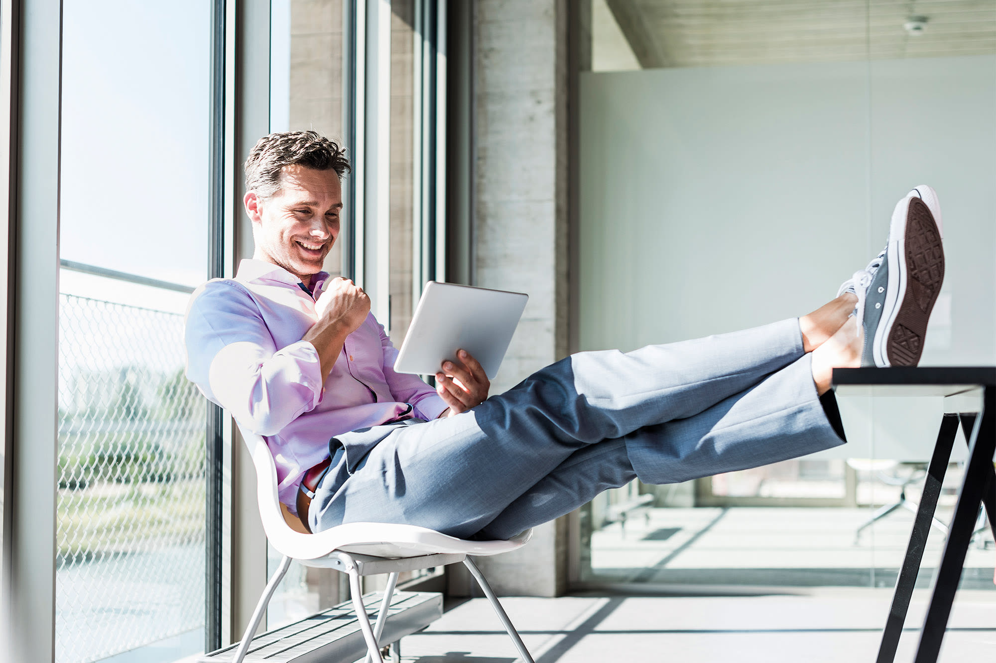 Moški v rožnati majici gleda na tablični računalnik - Elba BKS Bank